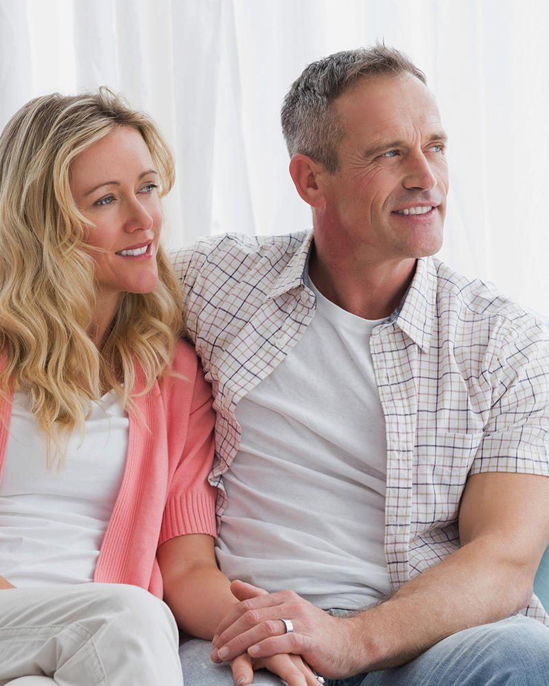 A couple sitting closely, smiling, and looking content and possibly rebuilding marriage.