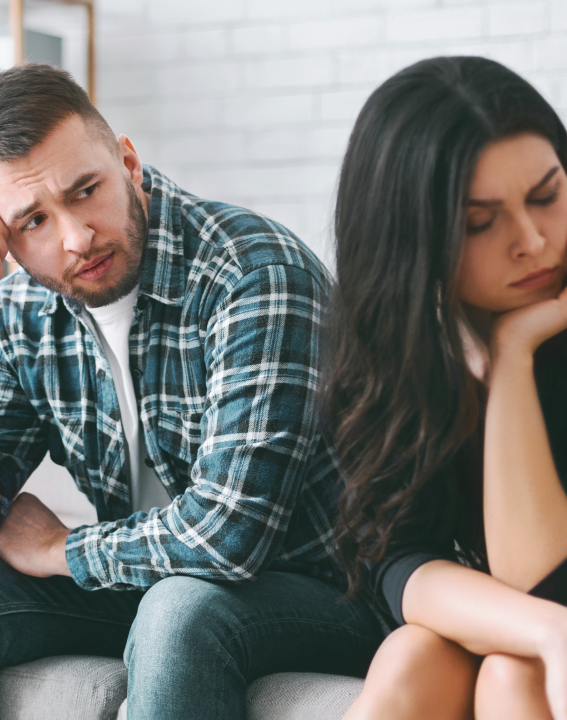 A man and a woman are sitting together, appearing to be having a serious or emotional conversation.