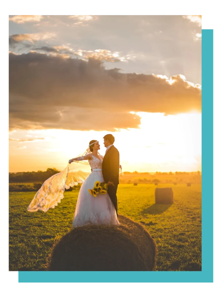 A couple in wedding attire stands romantically in a sunlit field, evoking themes of love and union.